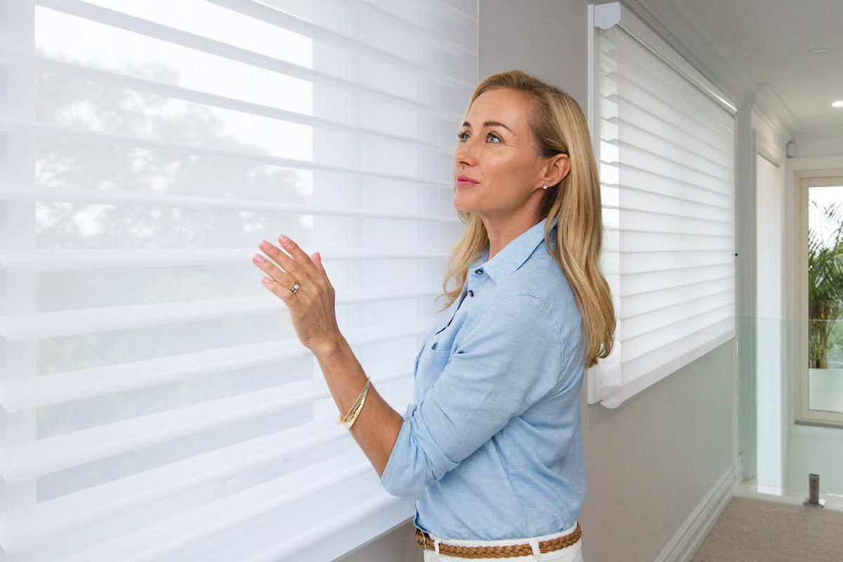 A woman standing in front of a window with white blinds